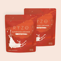 RYZE pumpkin spice superfood creamer packets with milk splash on orange-red background